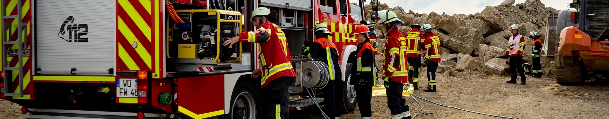 Feuerwehrleute bei einer technischen Hilfeleistung im Steinbruch, Einsatzleiter in weißer Weste.
